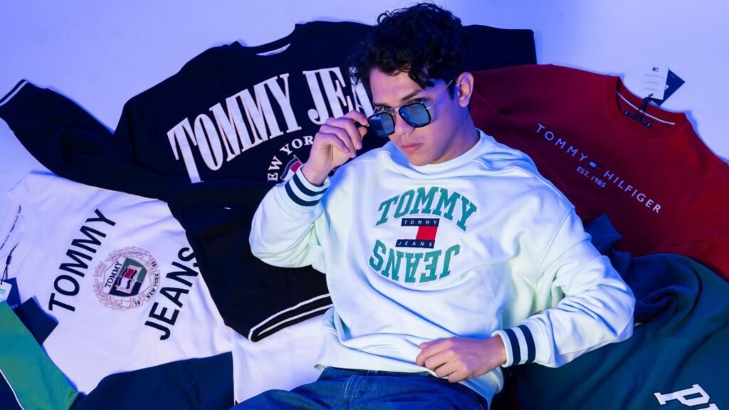 Joven con lentes de sol usando una sudadera de estilo urbano de Tommy Jeans de la tienda Doors.