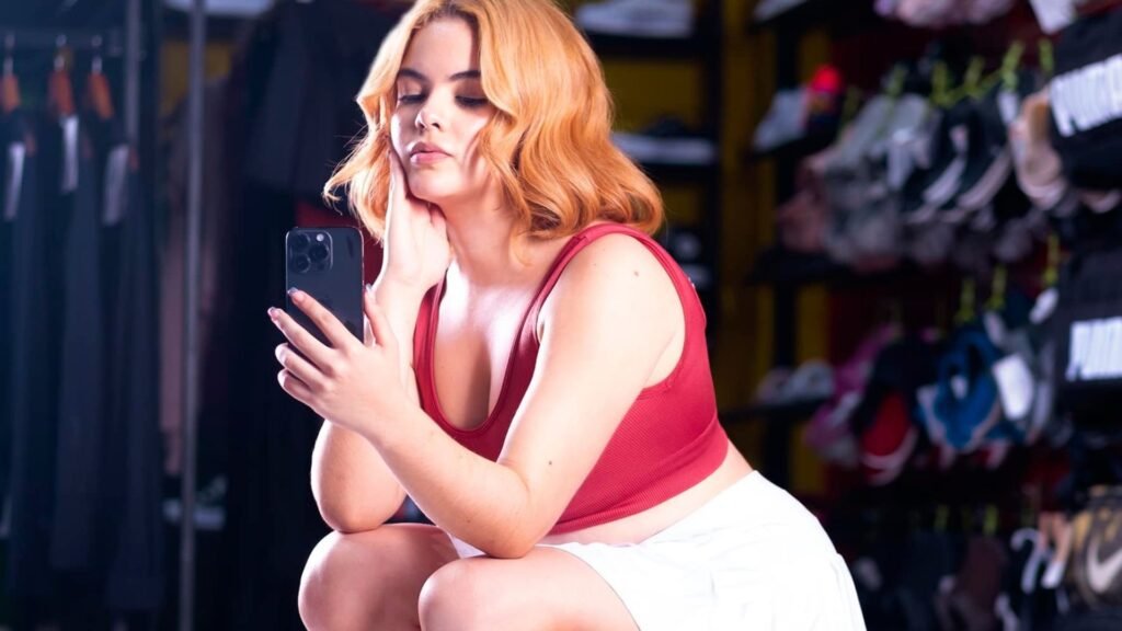 Mujer tomando una selfie con un outfit deportivo con falda blanca y top rojo en la tienda Time Out.