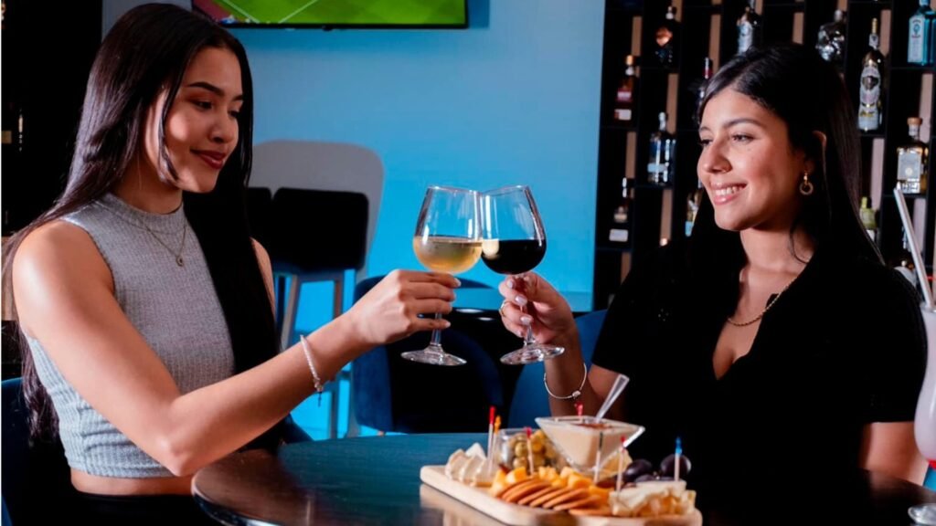 Dos mujeres brindando con copas de vino en Drink House.