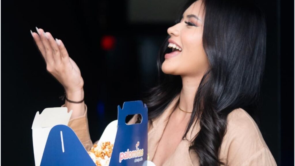 Mujer joven disfrutando felizmente de una caja de palomitas de Cinépolis y un refresco dentro de una de las salas de cine en Mall Premier Juticalpa.