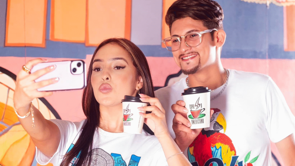 Una pareja joven tomándose una selfie mientras visten camisetas de Tiendas Pacer con diseños culturales de Honduras.