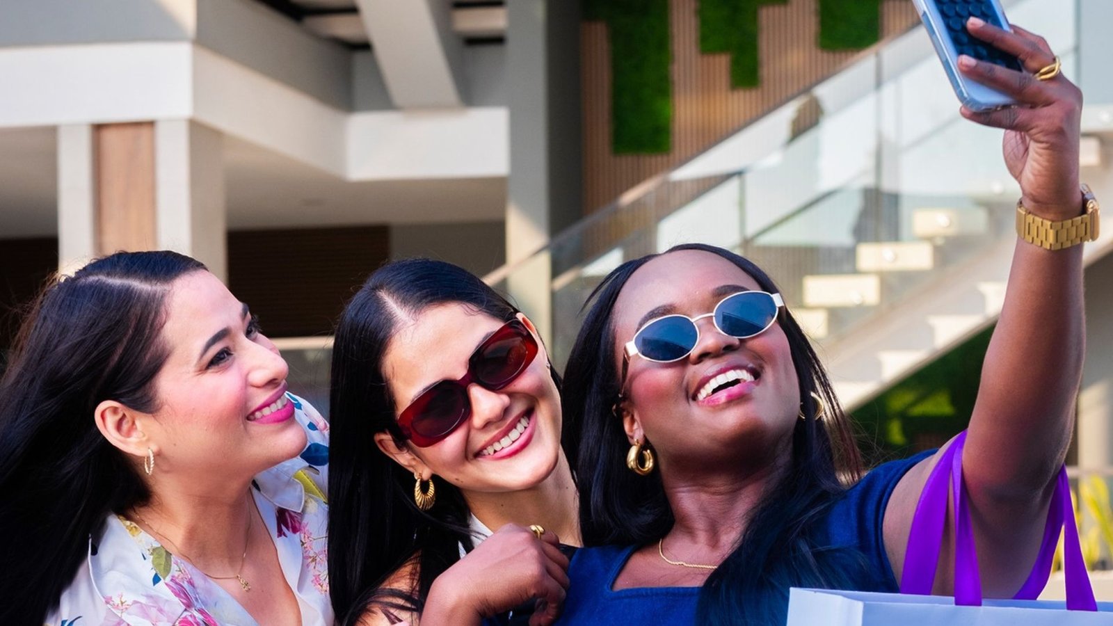 Tres amigas tomándose una selfie con bolsas de compras en Plaza Premier La Ceiba.