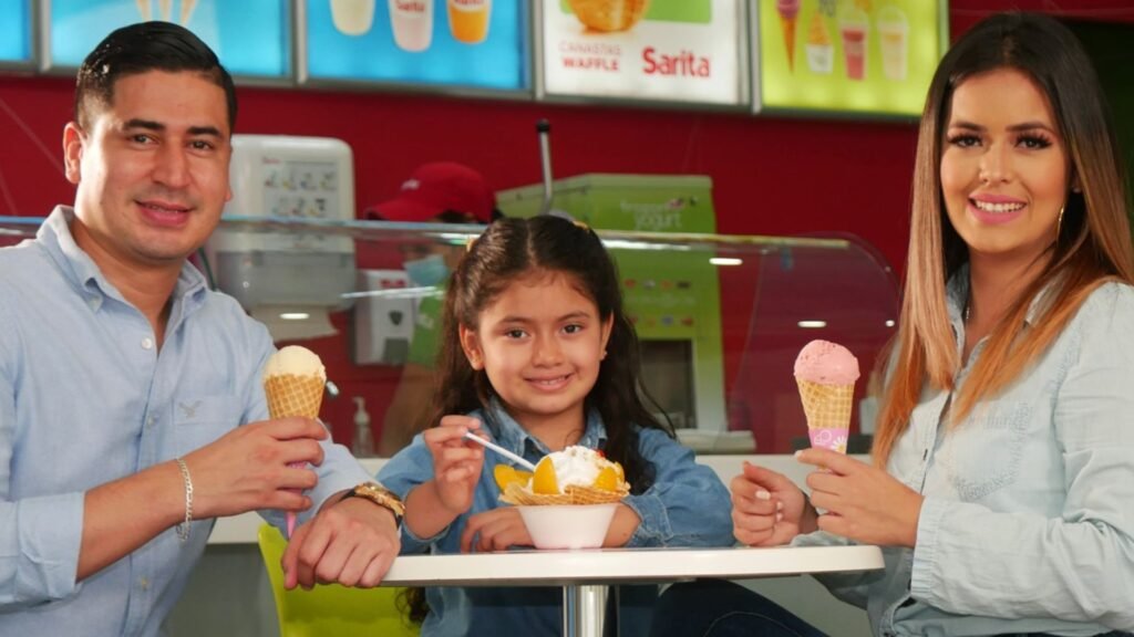 Una familia feliz, padre, madre e hija, compartiendo helados y postres fríos de Helados Sarita en el área de comidas de Mall Premier Comayagua.