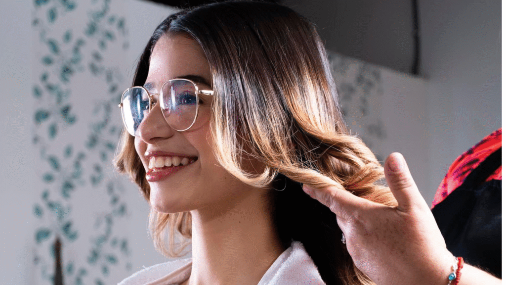 Estilista profesional creando ondas en el cabello de una joven sonriente en el salón de belleza Les Coquettes.