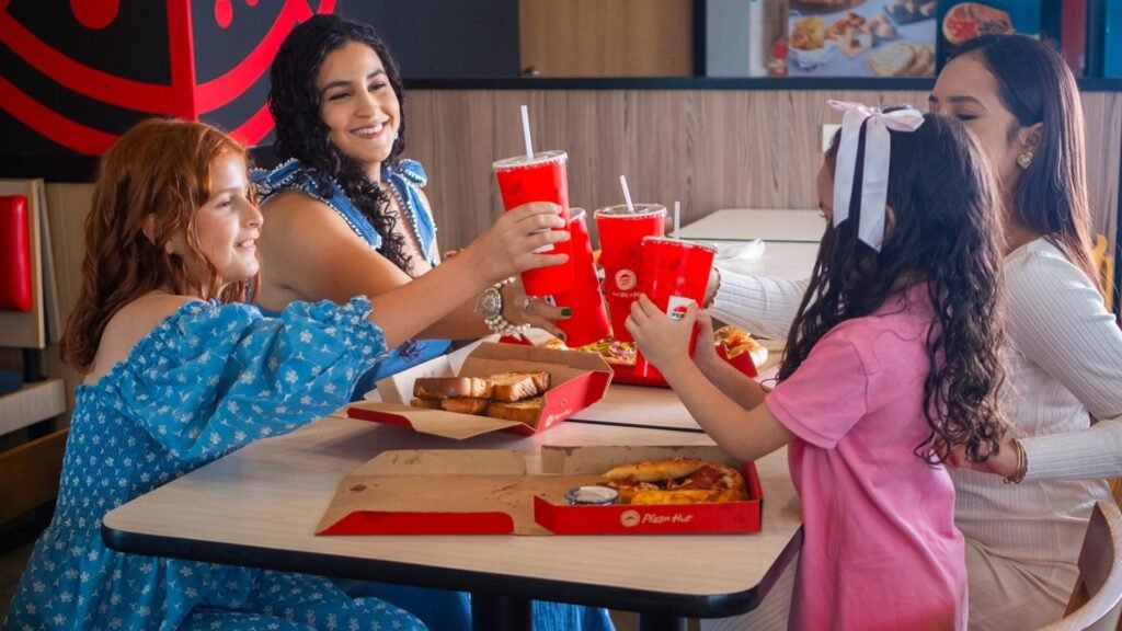 Mujeres sonriendo mientras disfruta de una rebanada de pizza en Pizza Hut de Catacamas.