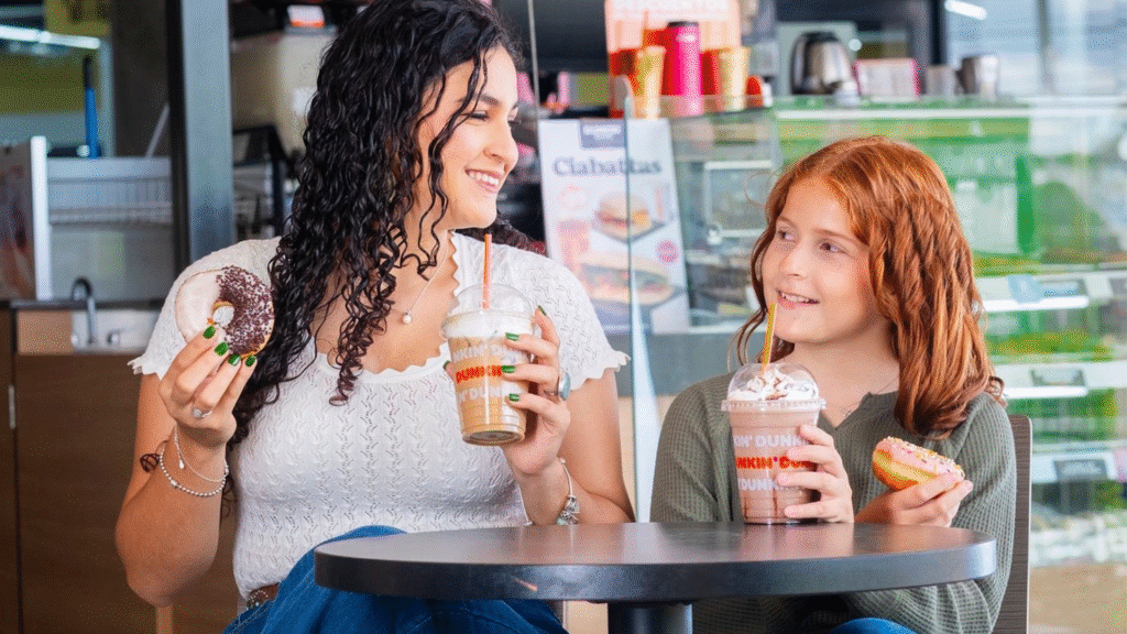 Madre e hija conversan alegremente mientras comen donas y bebidas de Dunkin' Donuts en Tegucigalpa.