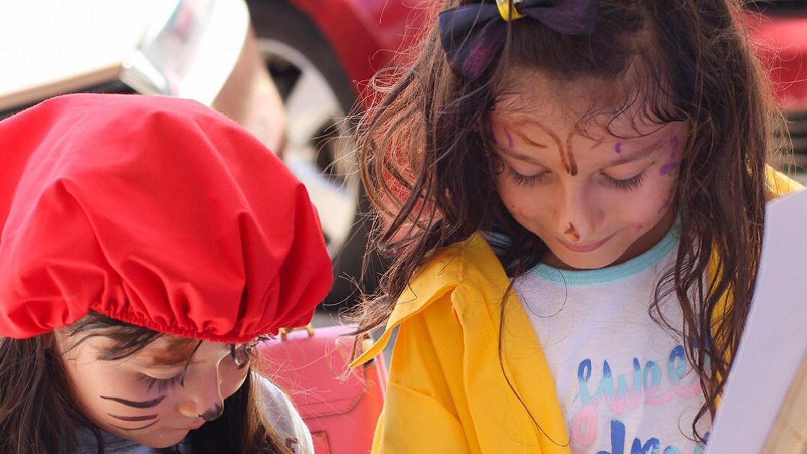 Dos niñas con las caras pintadas se divierten en una actividad de pintura durante el evento Spooktacular para niños en Plaza Premier.
