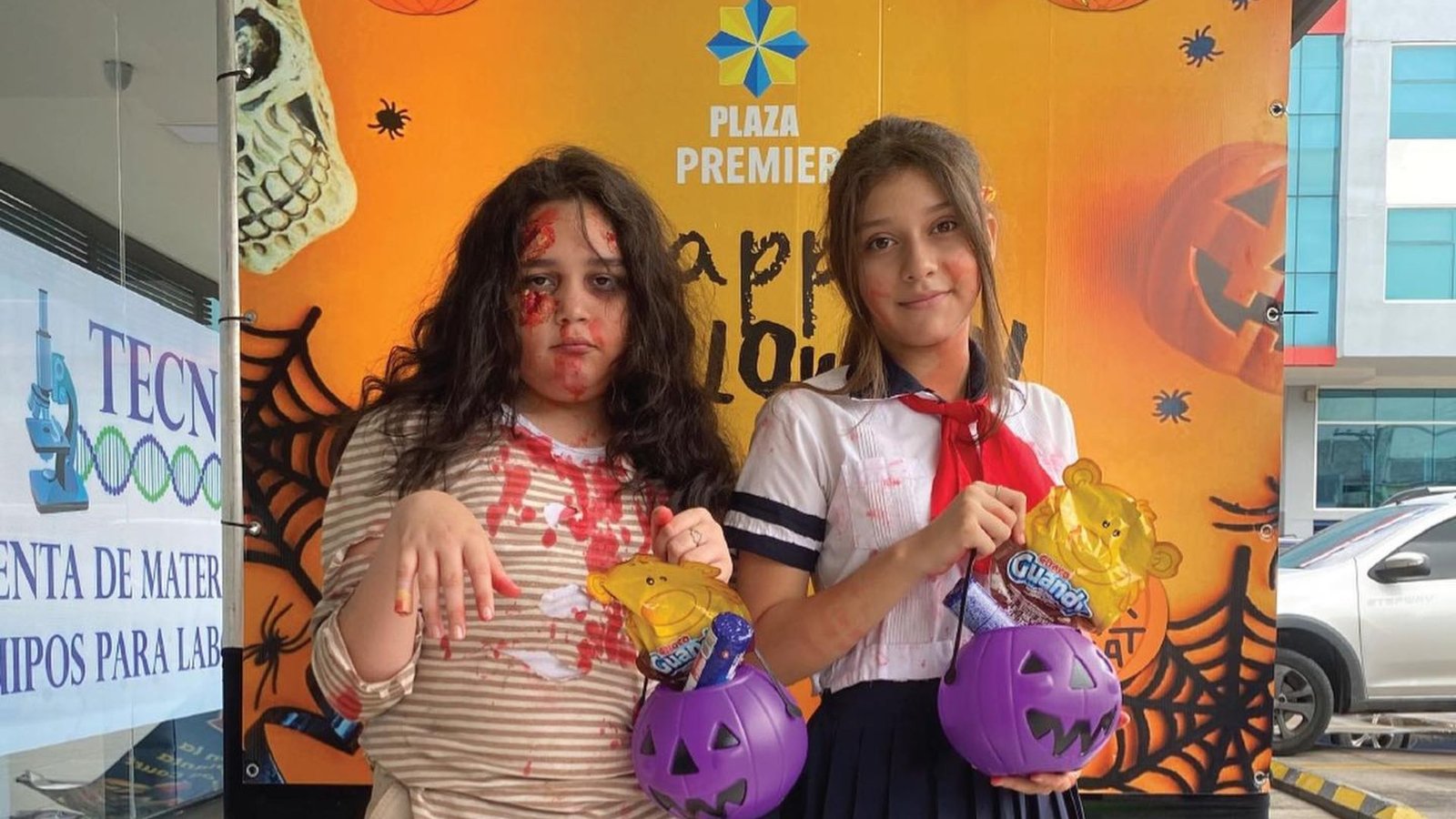  Dos niñas con disfraces creativos de Halloween, una de zombie y otra de colegiala, posan con sus calabazas para dulces en Plaza Premier evento Spooktacular