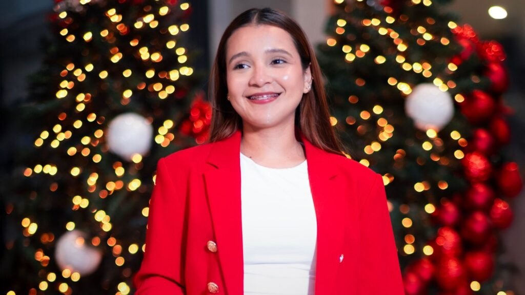 Retrato de mujer sonriendo con luces navideñas de fondo en Pasillos de Plaza Premier.