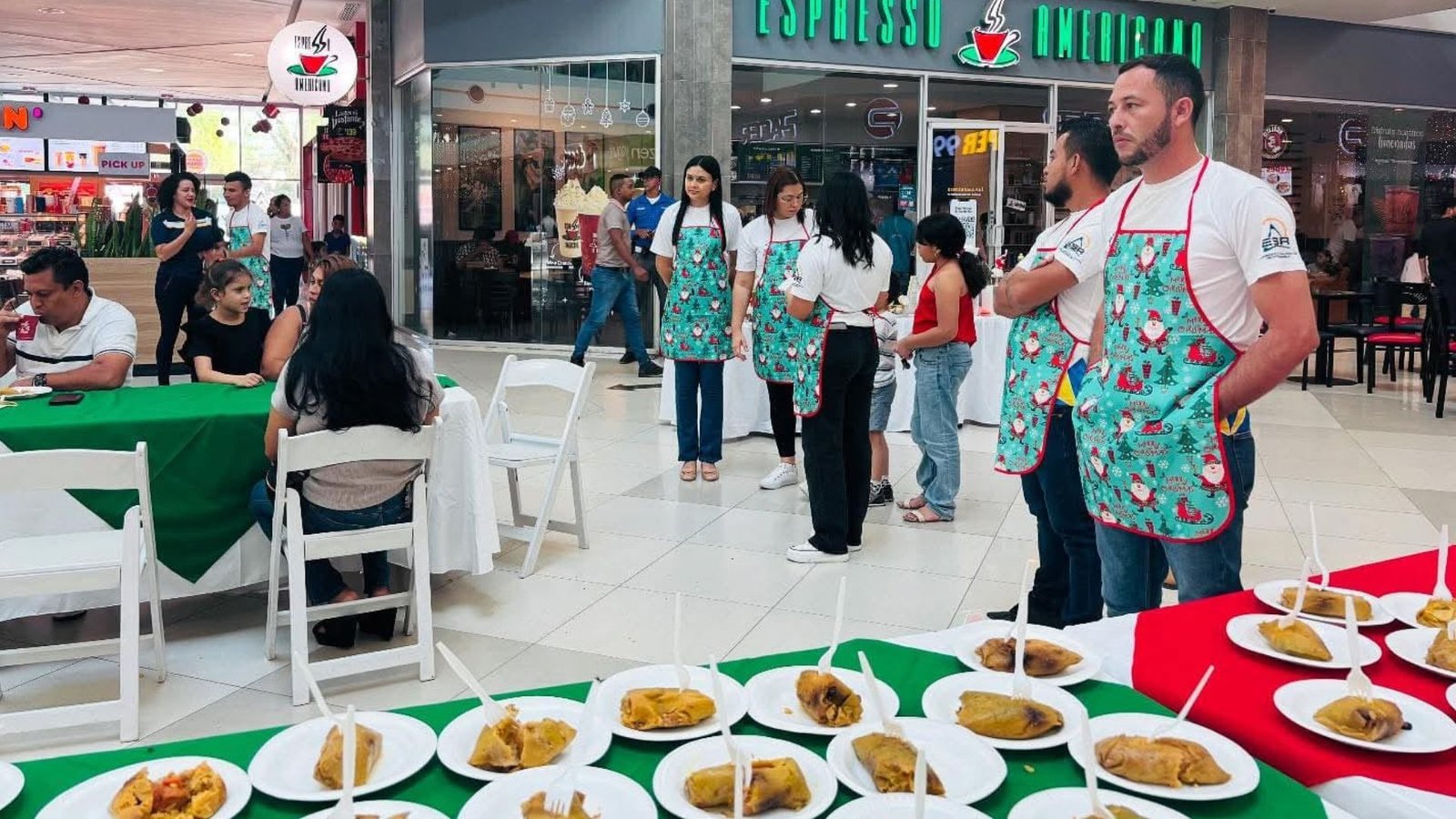 Equipo de Mall Premier Juticalpa con delantales navideños sirviendo platos de nacatamales.