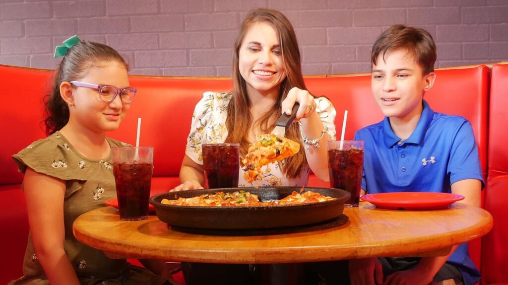Familia compartiendo una pizza en el restaurante Pizza Hut de Mall Premier.